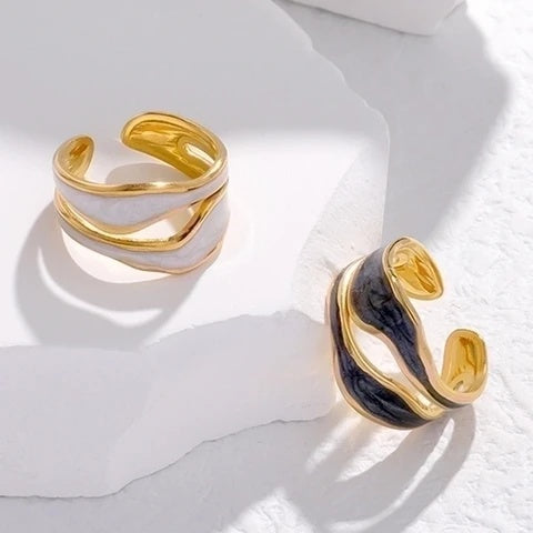 Gold and black open ring on a white marble surface