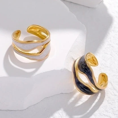 Gold and black open ring on a white marble surface