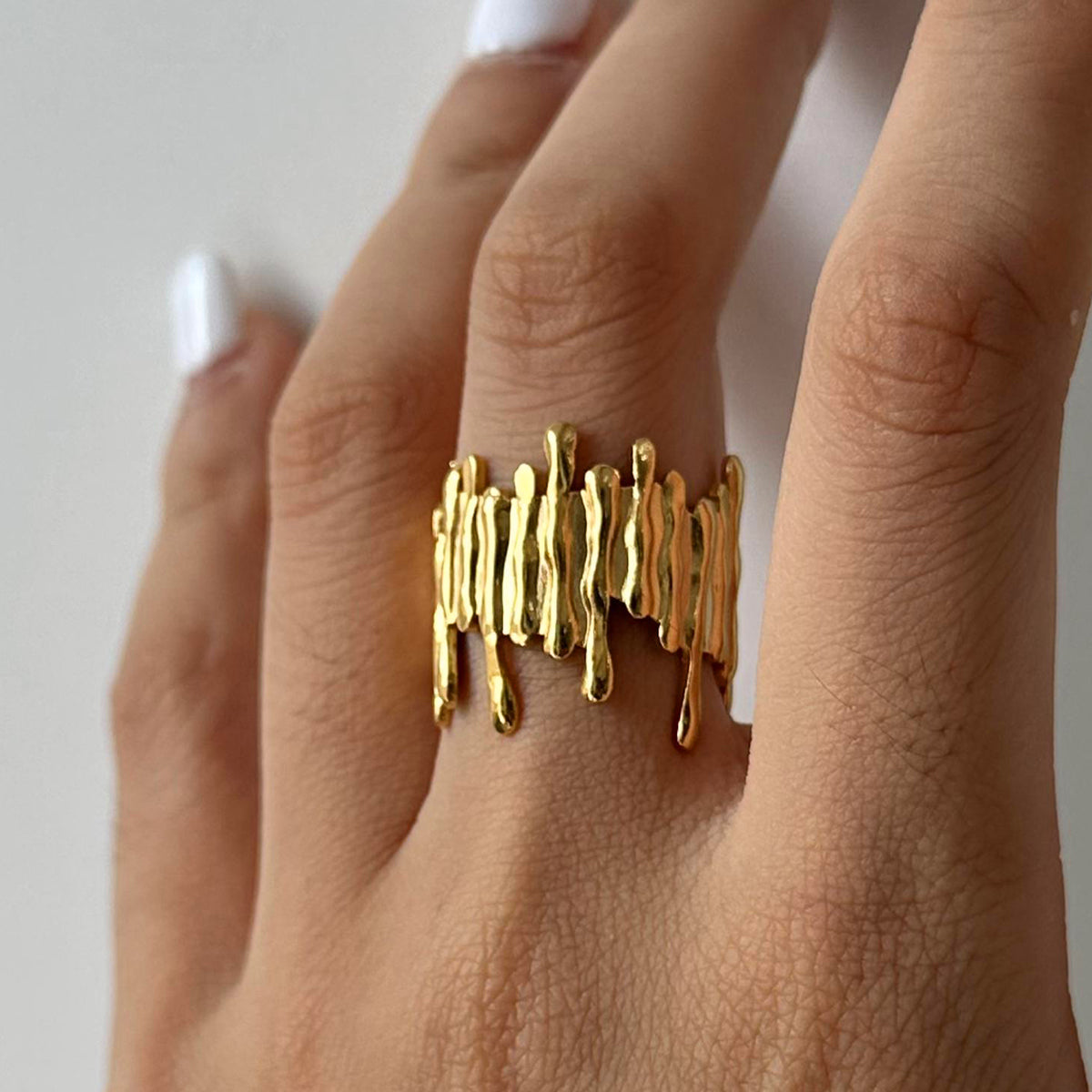 Gold ring on a finger against a neutral background