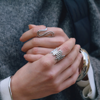 Close-up of a hand wearing multiple silver rings with a blurred background