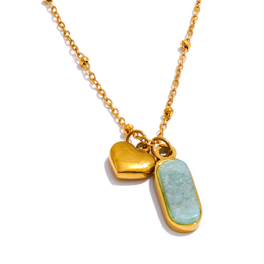 Gold necklace with heart and green stone pendant on a white background
