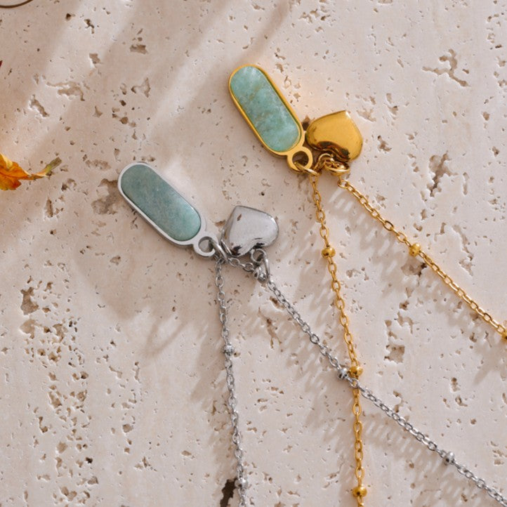 Two necklaces with turquoise and gold pendants on a textured beige surface.