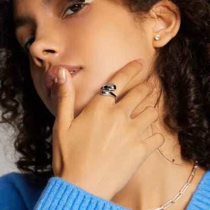 Woman wearing a silver ring and earring, with a neutral background