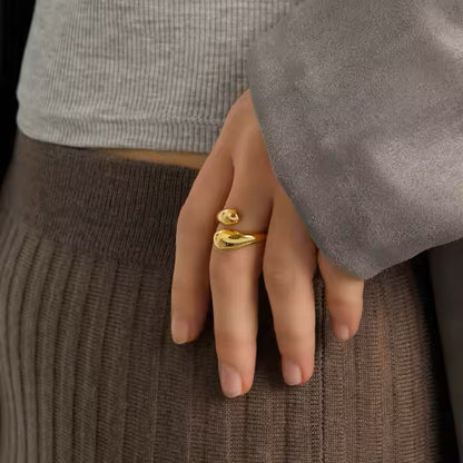 Hand wearing a gold ring with a plain background
