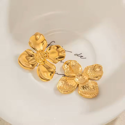 Gold flower-shaped earrings on a white surface