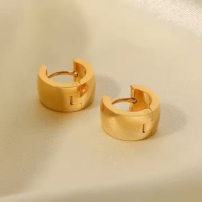 Pair of gold hoop earrings on a beige fabric background