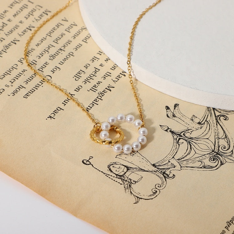 Gold necklace with a round pendant featuring pearls on an old book page.