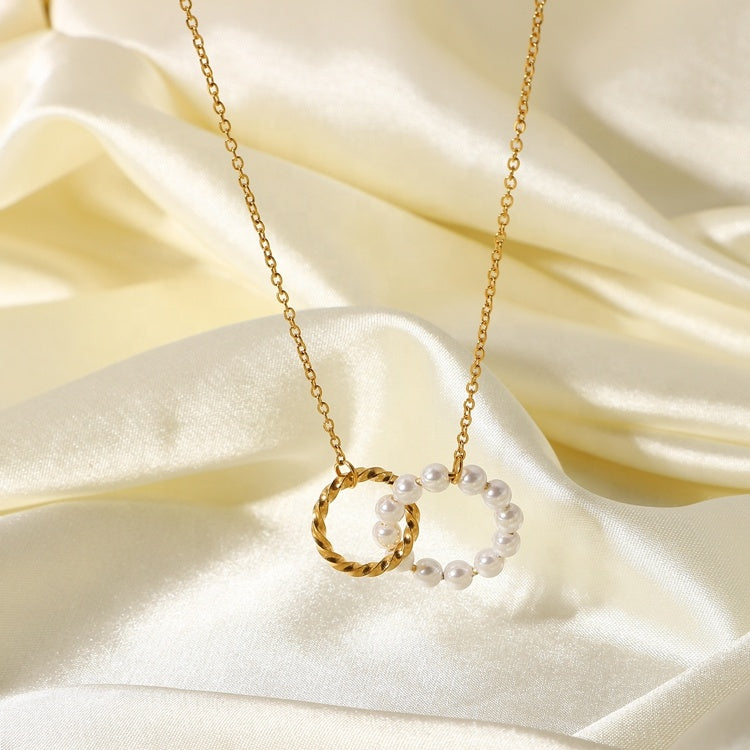 Gold necklace with a pearl pendant on a soft beige fabric background