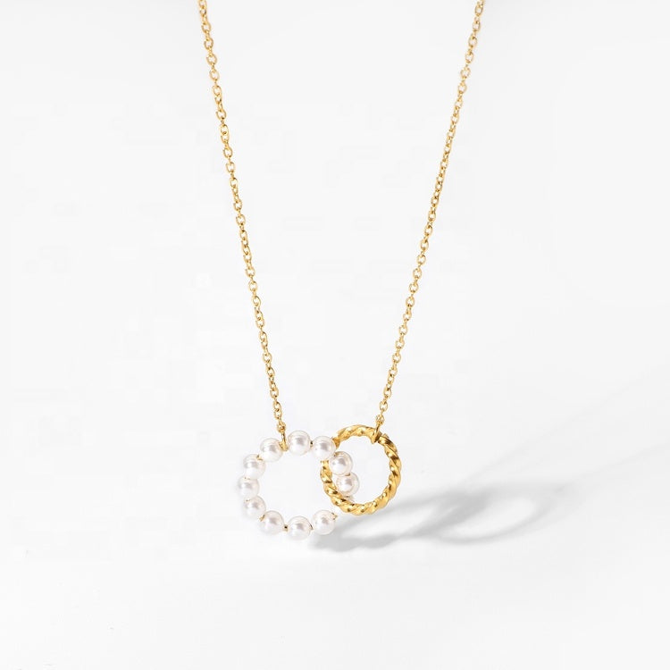 Gold necklace with a circular pendant featuring pearls on a white background