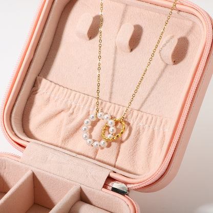 Gold necklace with a circular pendant and pearl beads in a pink jewelry case.