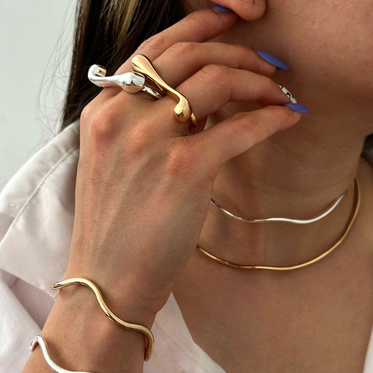 a hand wearing two statement double rings in silver and gold