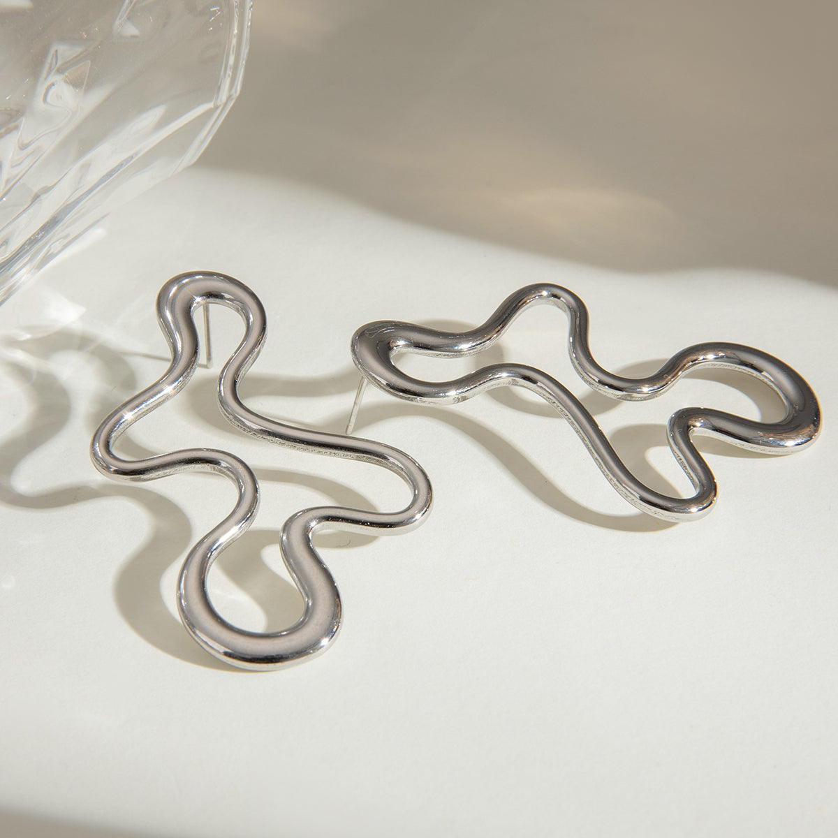 Silver abstract earrings on a light background