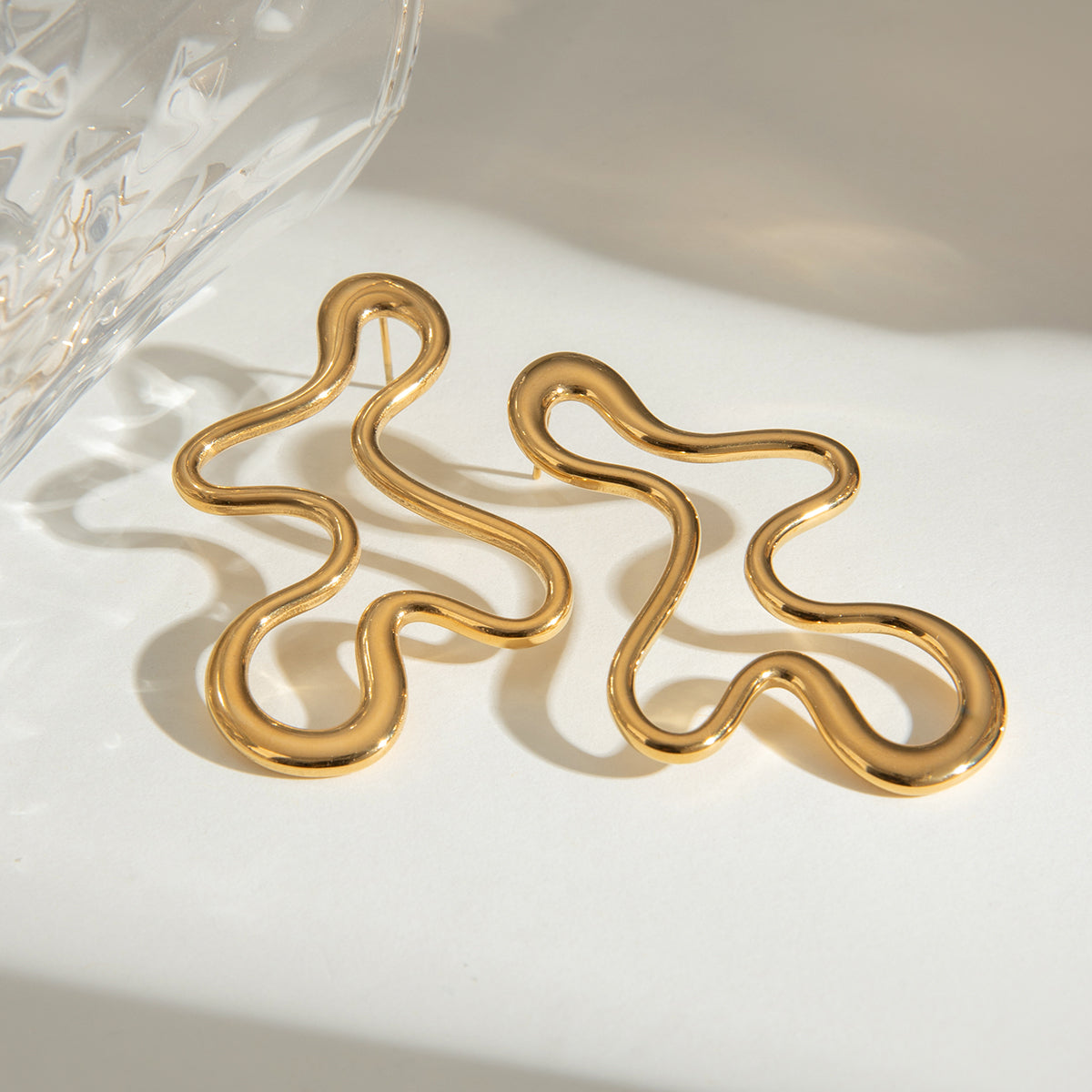 Elegant gold abstract earrings on a light background