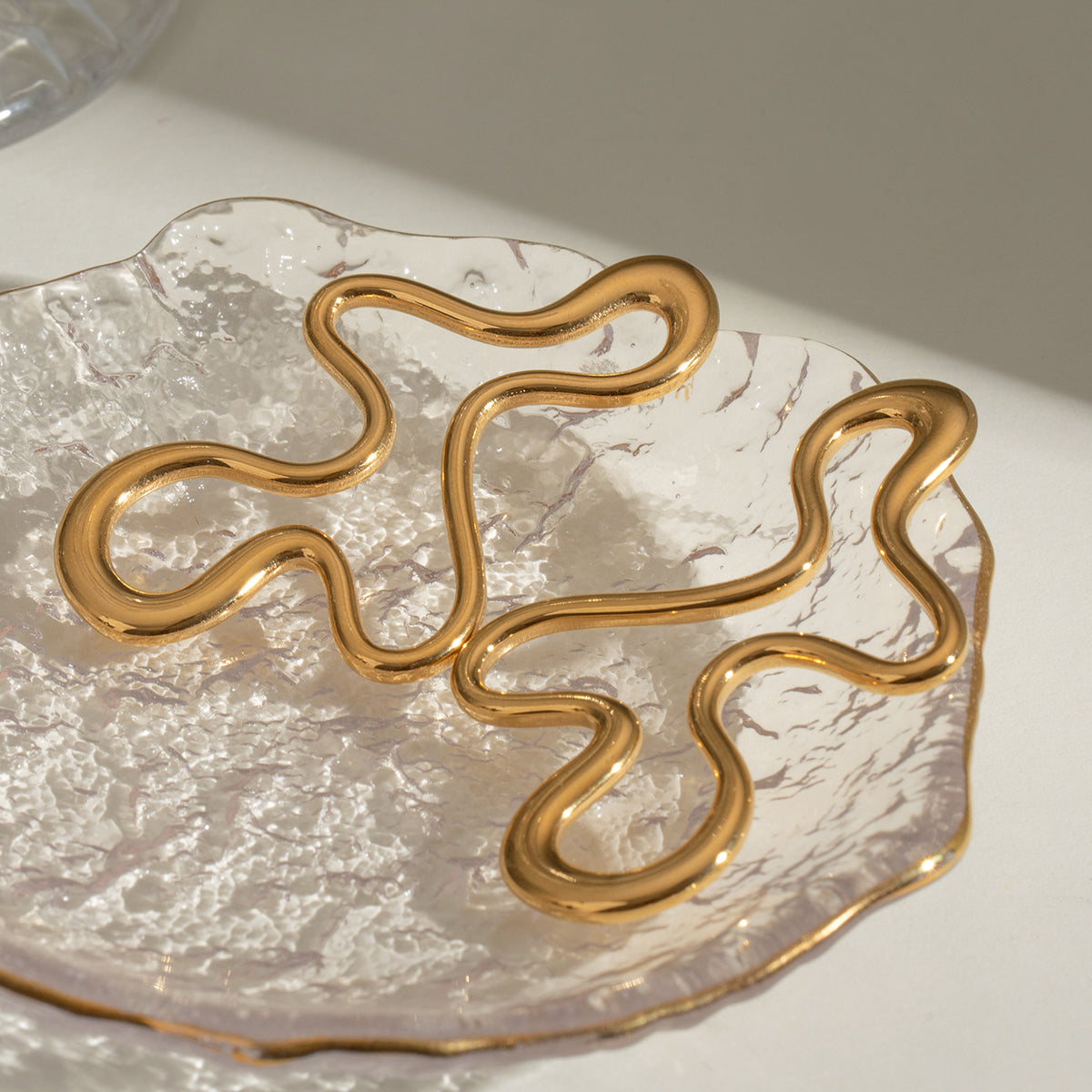 Gold statement earrings on a textured white surface