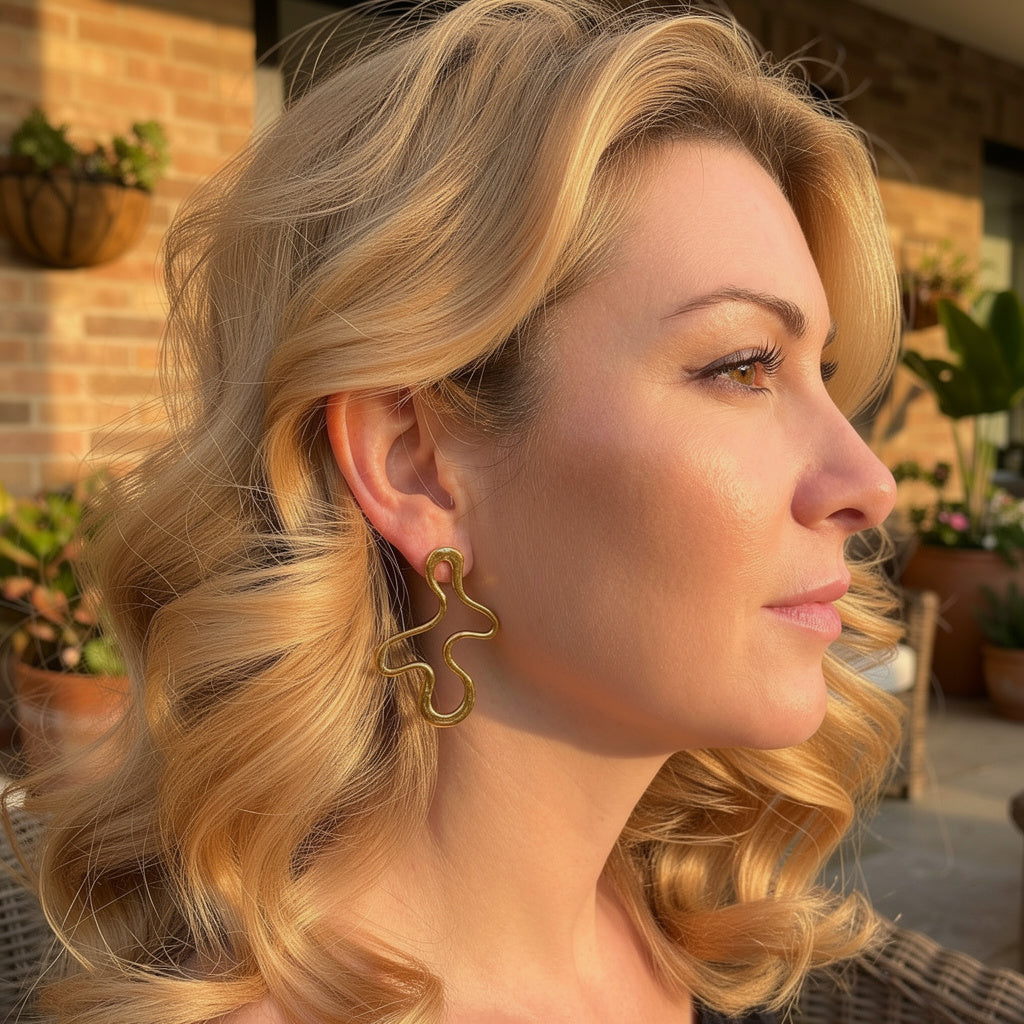 Woman with blonde hair wearing gold statement earrings outdoors