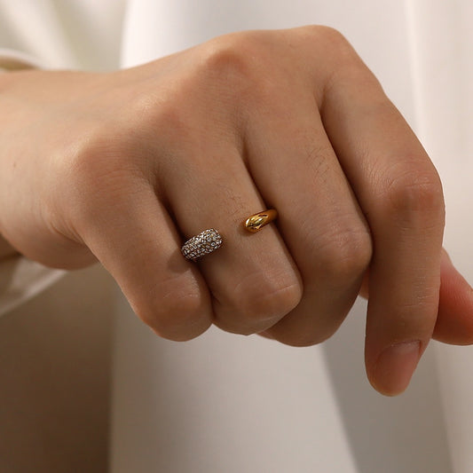Close-up of a hand wearing a gold stainless steel ring on a plain background