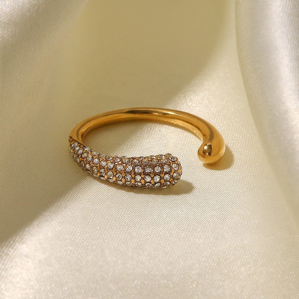 Gold ring with embedded stones on a beige fabric background