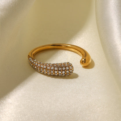 Gold ring with embedded stones on a beige fabric background
