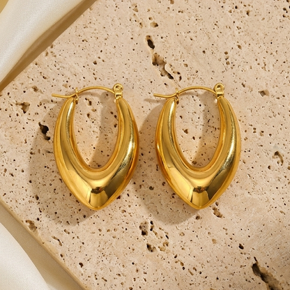Pair of chunky gold hoop earrings with a sculptural teardrop shape, pointed bottom, polished finish, and hinged closures.