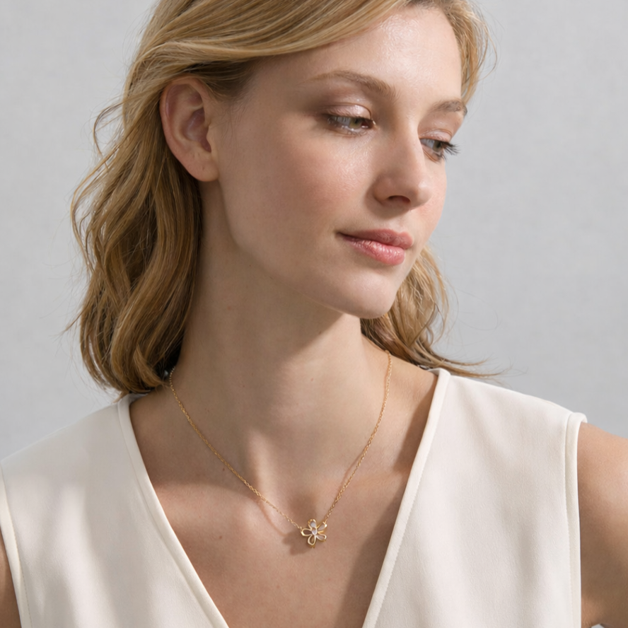 Woman wearing a gold necklace with a delicate pendant against a neutral background