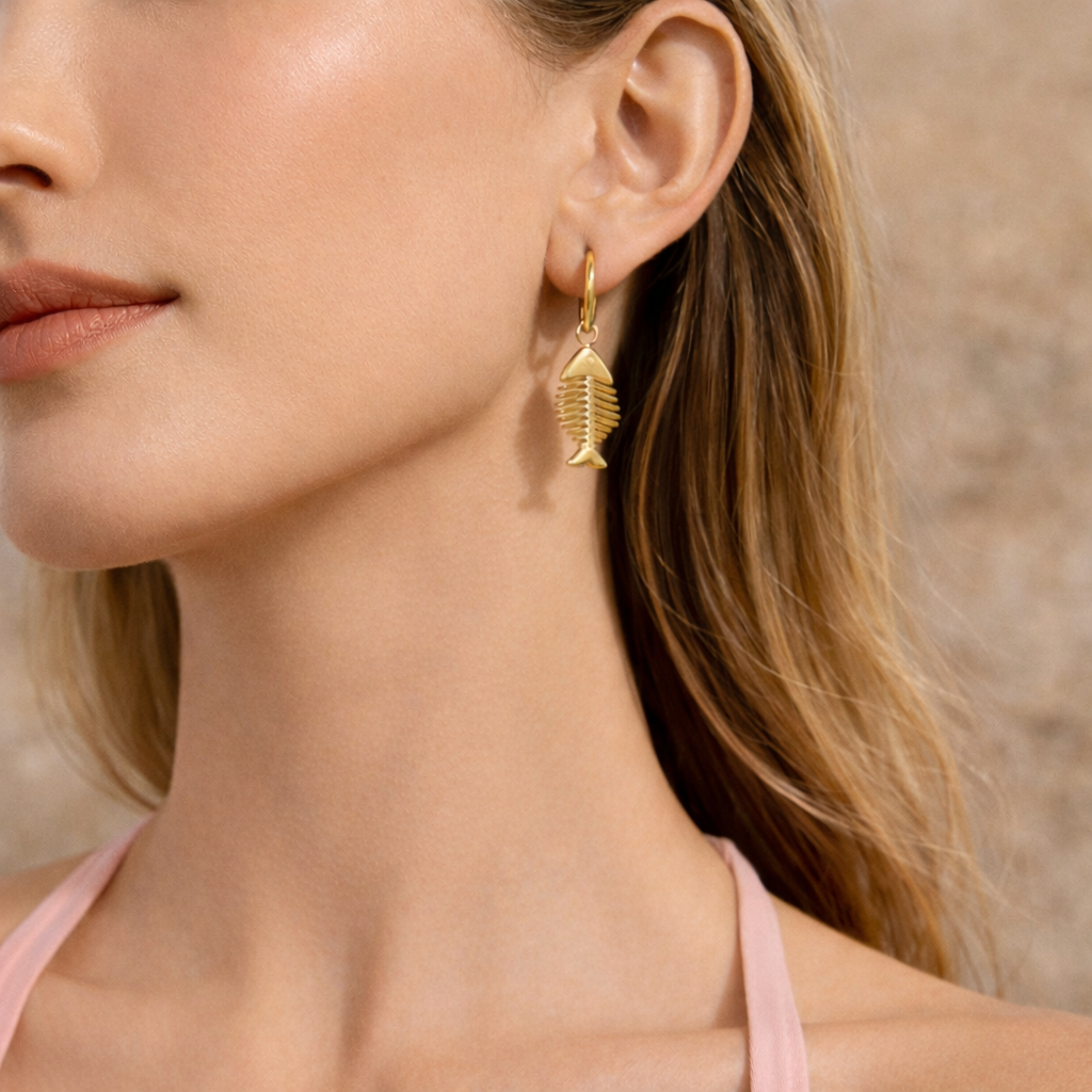 Close-up of a woman wearing gold earrings with fishbone shape with a neutral background