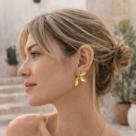 Woman wearing gold earrings with a blurred outdoor background