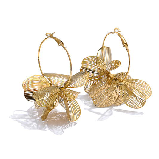 Gold statement hoop earrings with leaf-like designs on a white background