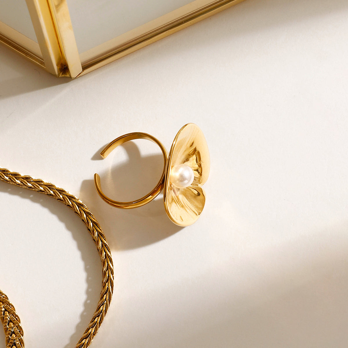 Elegant gold ring with pearl on a light beige surface