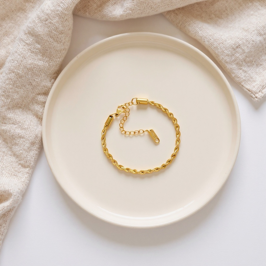 Gold chain bracelet on a beige plate with a beige cloth background