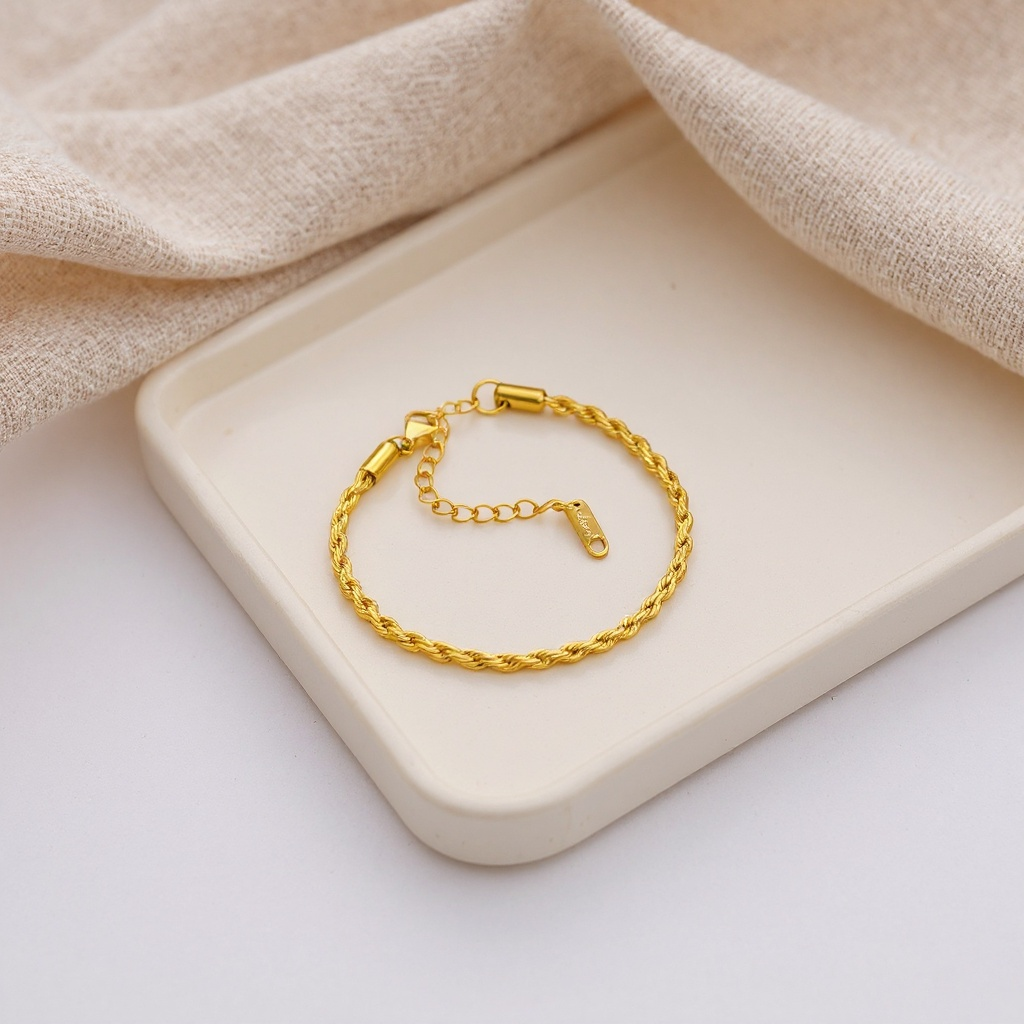 Gold bracelet on a beige tray with soft fabric background