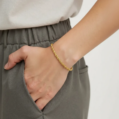 Gold bracelet on a wrist with a neutral background
