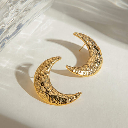 Gold crescent moon earrings on a white surface