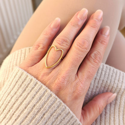 person wearing large gold ring with heart design
