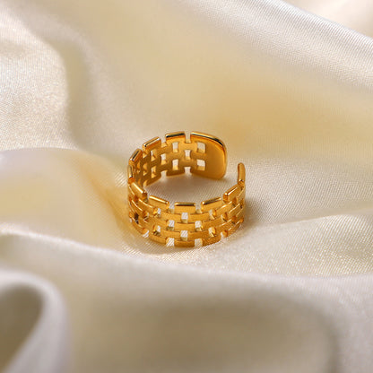 Gold ring with a geometric design on a white fabric background