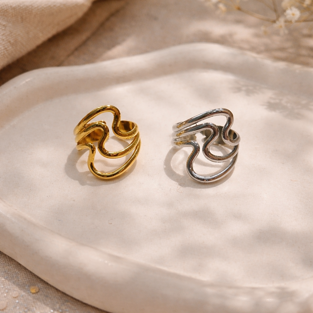 Gold and silver statement rings on a textured beige surface