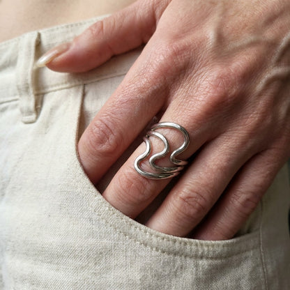 Hand wearing a subtle silver ring on a light-colored fabric background