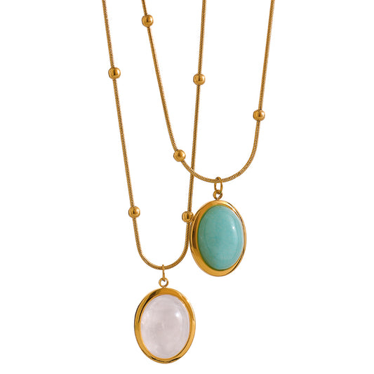 Two gold necklaces with gemstone pendants on a white background