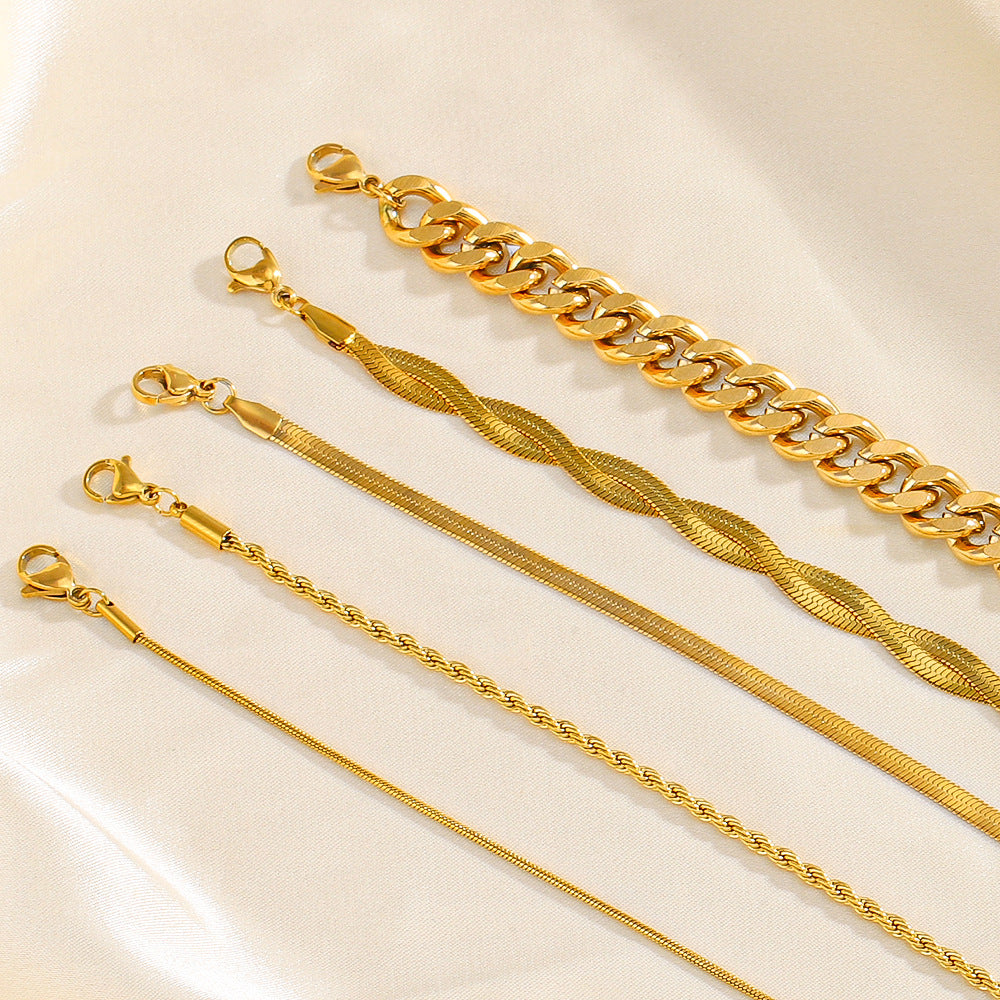 Five gold bracelets of different designs on a light beige background