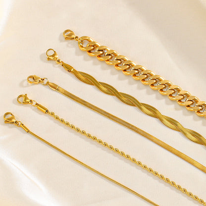 Five gold bracelets of different designs on a light beige background