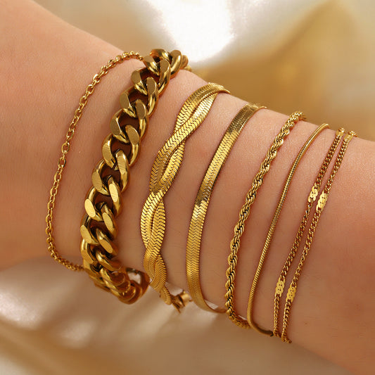 Gold bracelets on a wrist against a neutral background