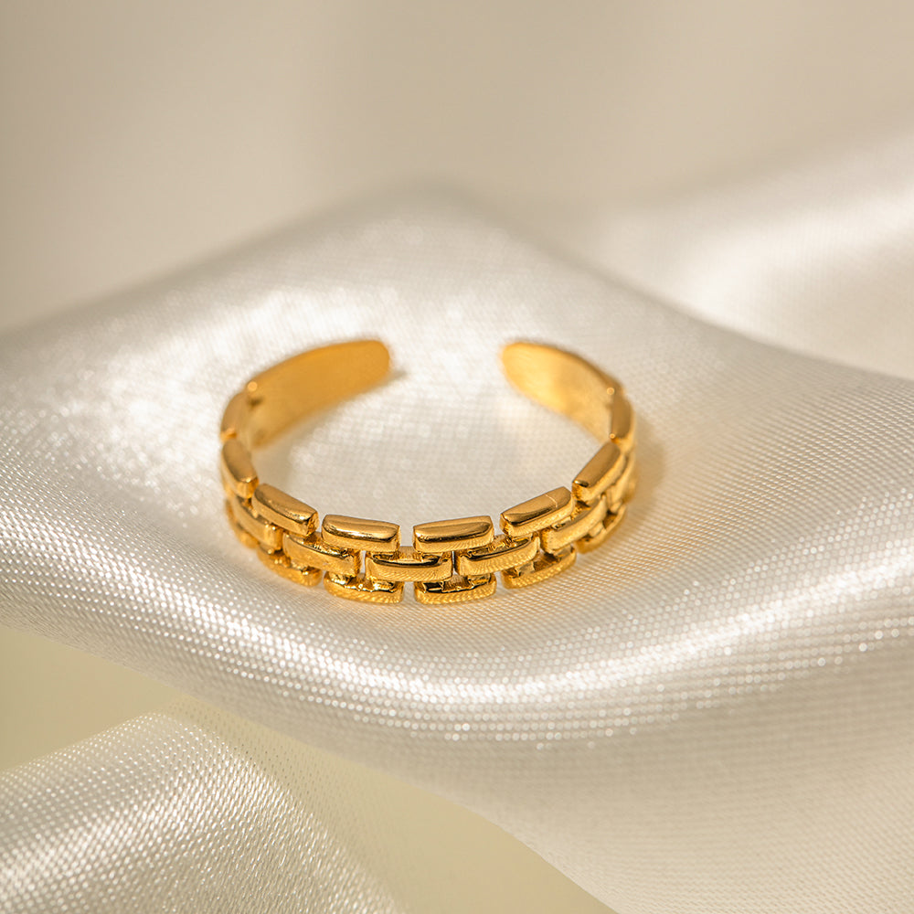 Gold stainless steel ring on a textured white surface