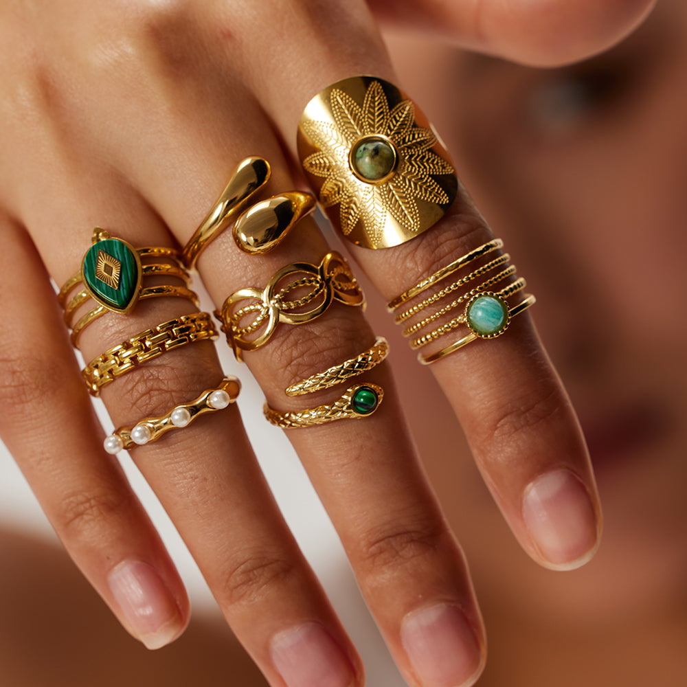 Hand wearing multiple gold rings with gemstones on a blurred background