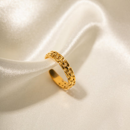 Minimalist gold chain ring on a soft beige fabric background