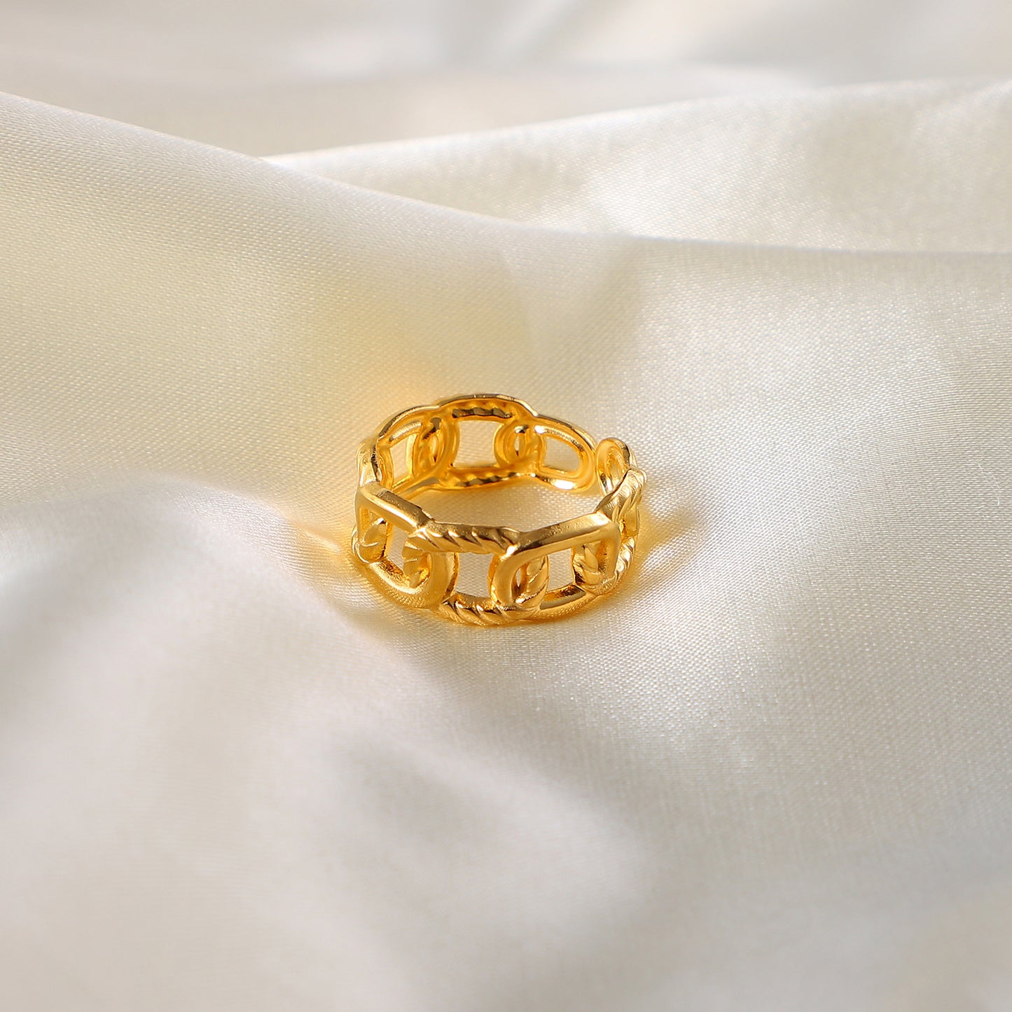 Gold stainless steel chain ring on a soft white fabric background