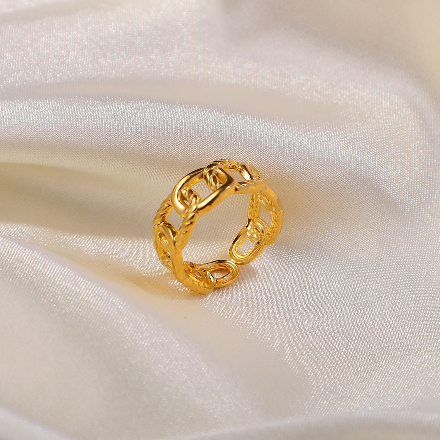 Gold chain ring on a white satin background