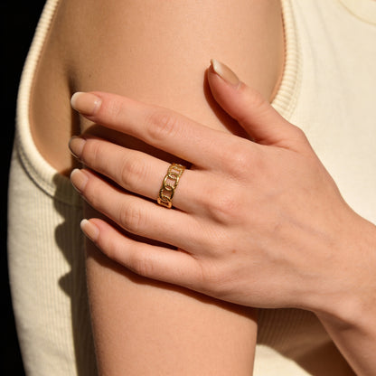 Hand wearing a gold ring on a neutral background