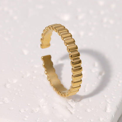 Simple gold ring with a textured design on a light gray background