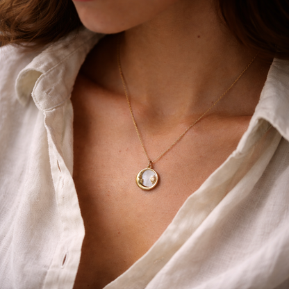 Close-up of a person wearing a delicate gold necklace with a round pendant.