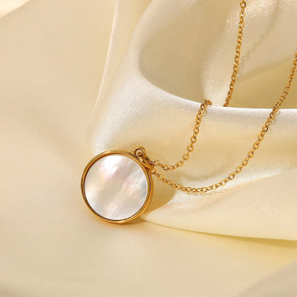 Gold necklace with a round pendant on a beige fabric background