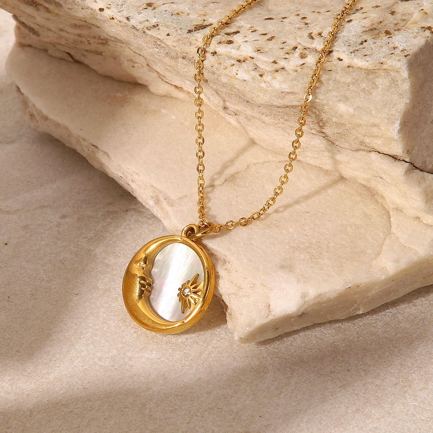 Gold necklace with a pendant on a stone surface
